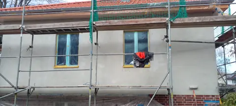 Fassade vorher: Gerüst mit grauem Grundputz